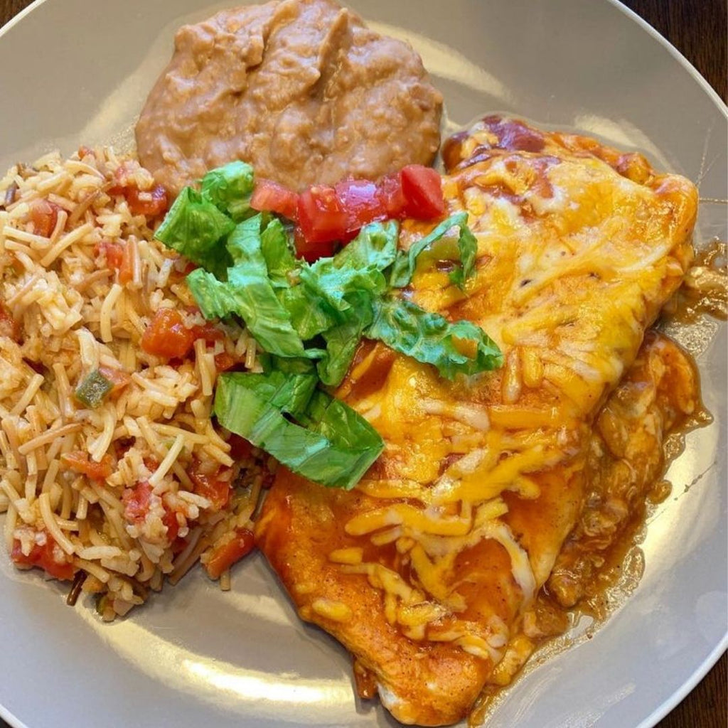 Plate of Enchilada with rice and refried beans.