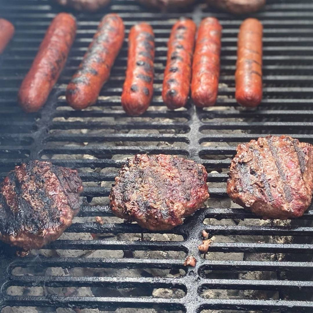 Bison Burgers and Hot Dogs cooking on grill.