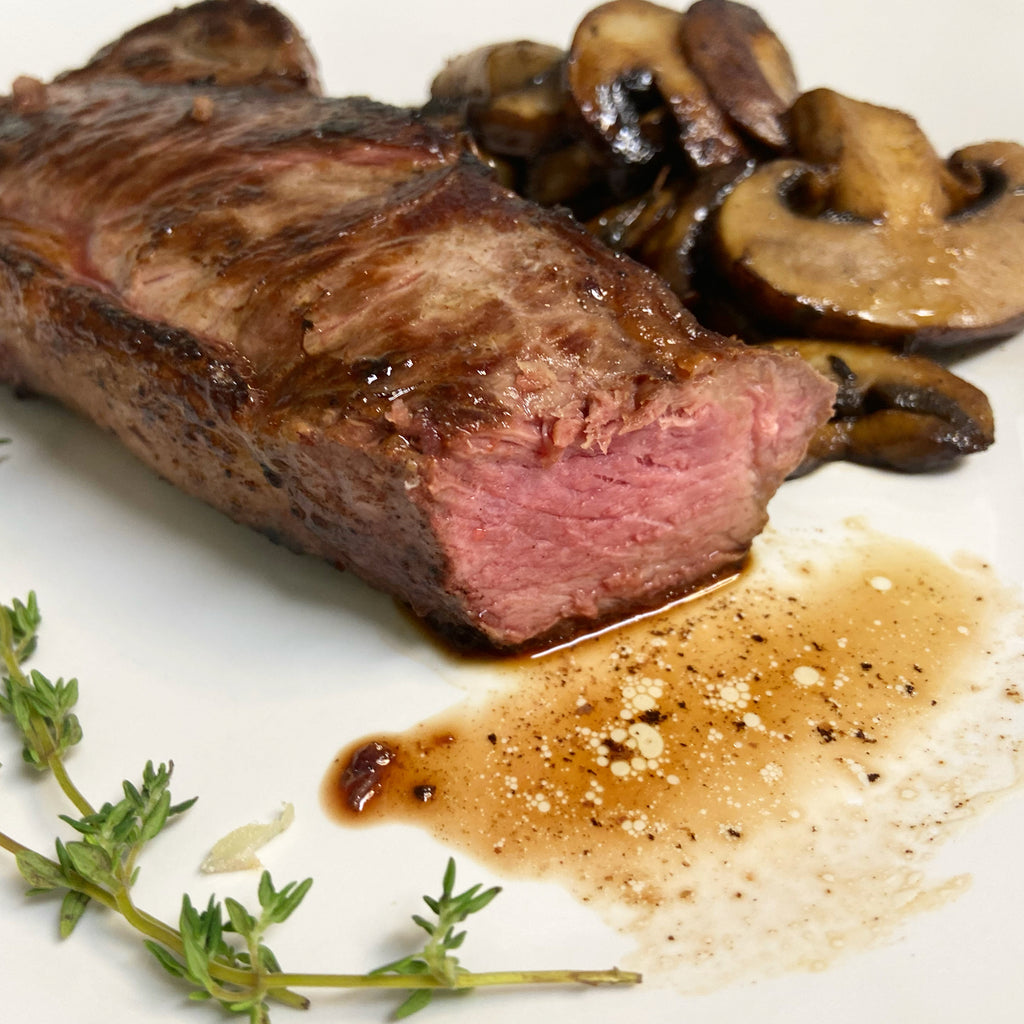 Bison NY Strip Steak cooked medium rare with mushrooms and thyme.