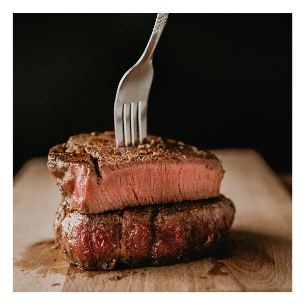 Cooked Bison Steak, cut in half, stacked with fork in top.