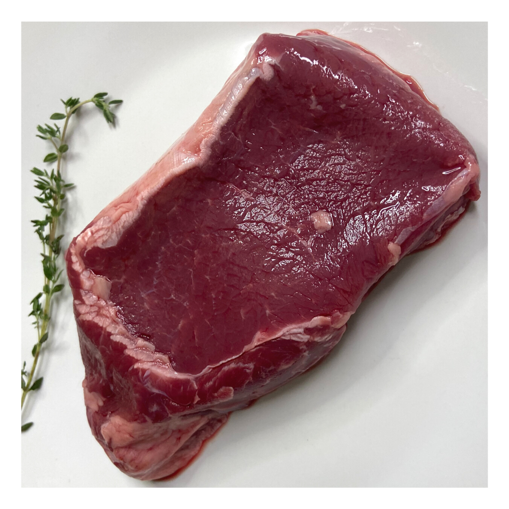 Raw bison ribeye steak on white plate.
