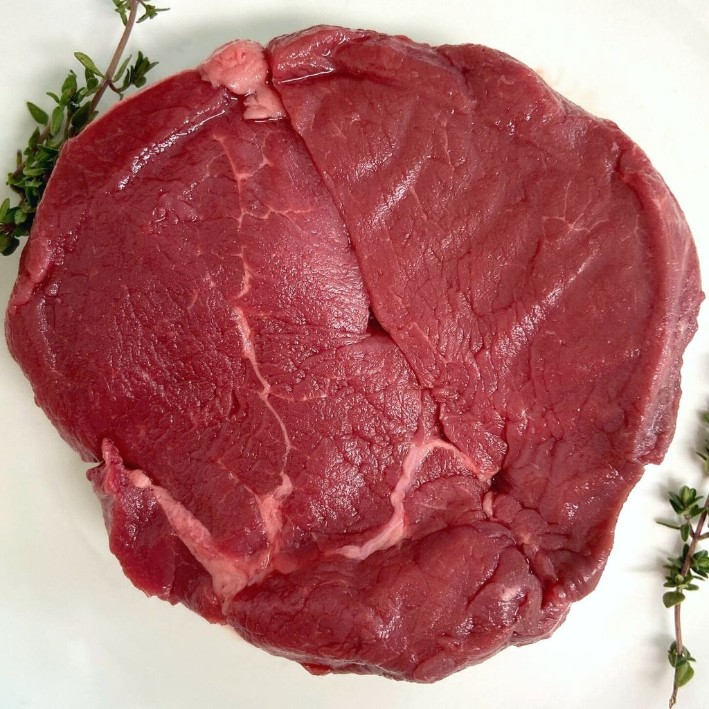 raw bison filet mignon with thyme sprigs.