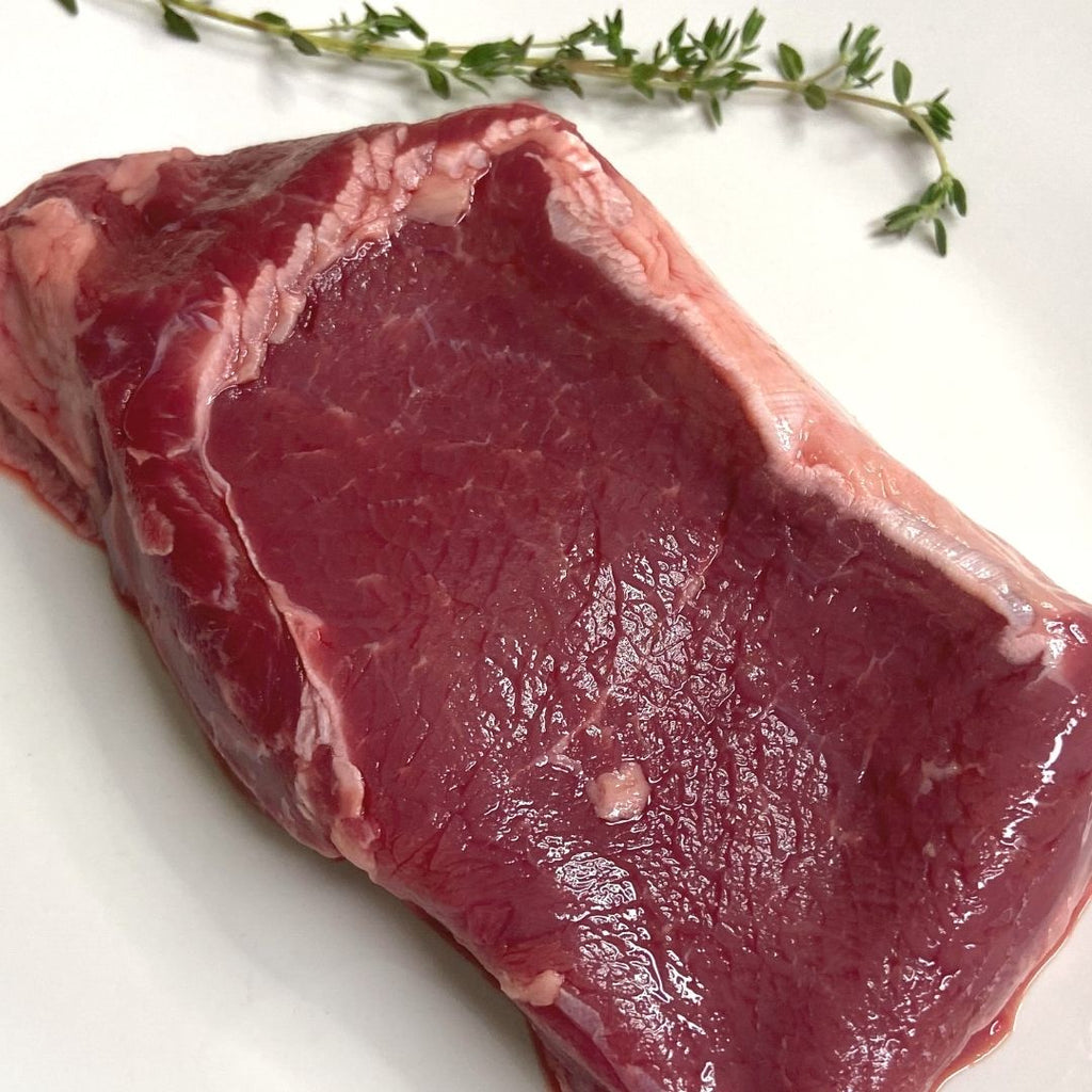 raw bison ribeye steak with sprig of thyme.
