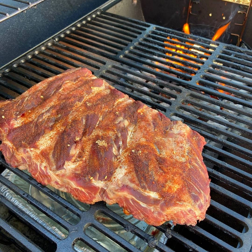 Raw Rack of Bison Back Ribs on the grill with fire.