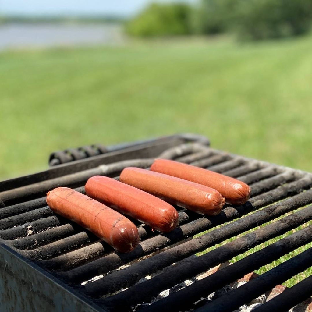Bison Hot Dogs on the grill in a grassy park.