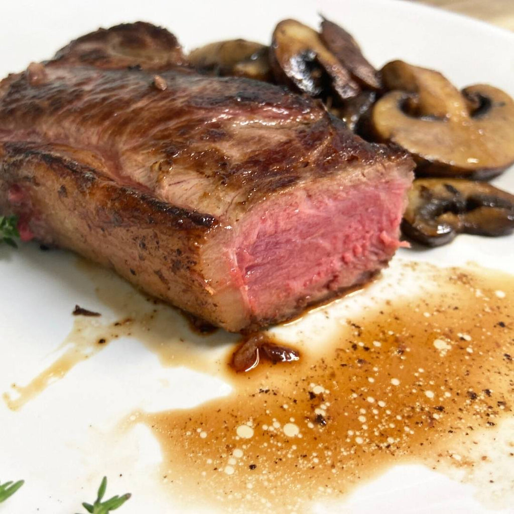Bison NY strip steak cooked rare with side of mushrooms.