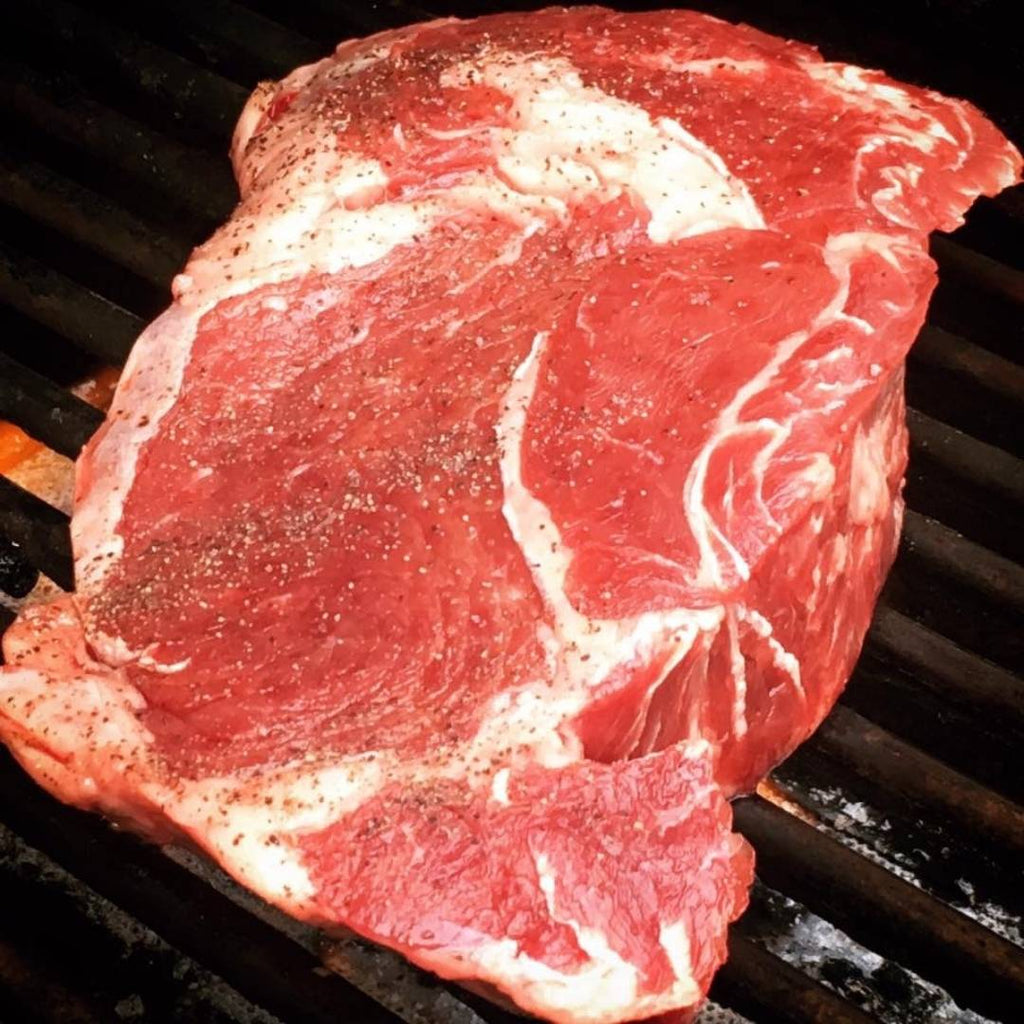 Raw Extra Thick Bison Ribeye Steak on Grill.