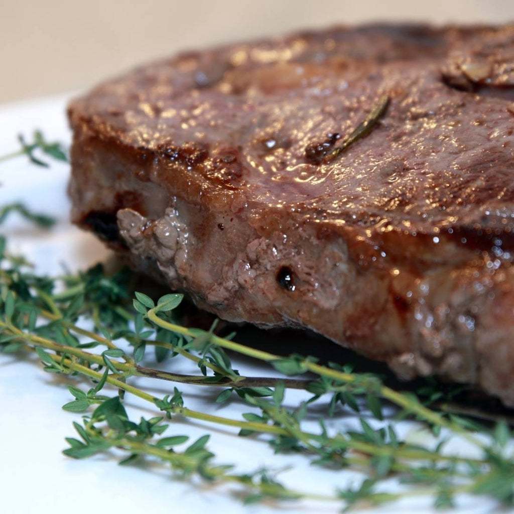 Extra Thick Bison Ribeye, cooked with thyme sprigs garnish.