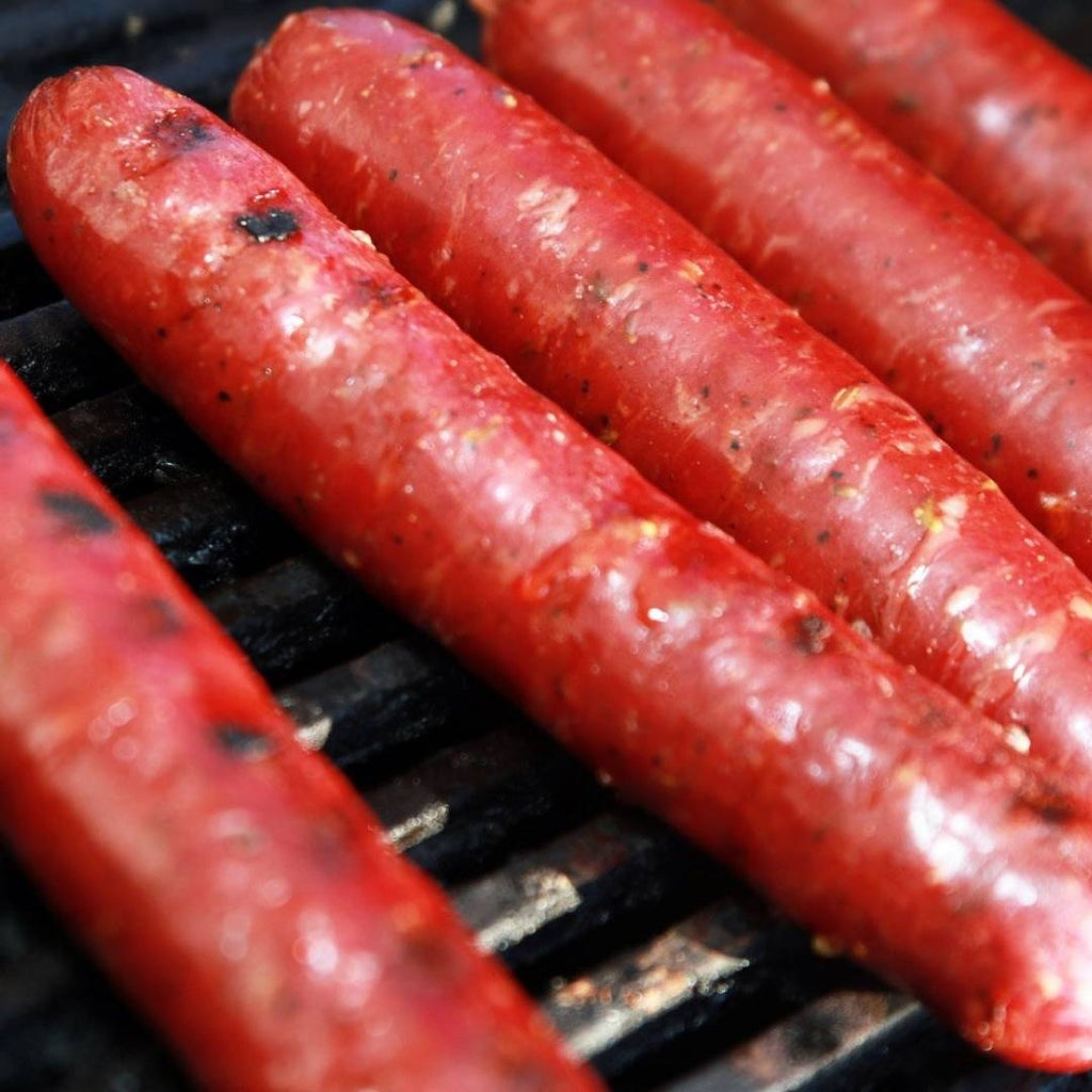 5 links of Spicy Elk Sausage cooking on grill, close up.