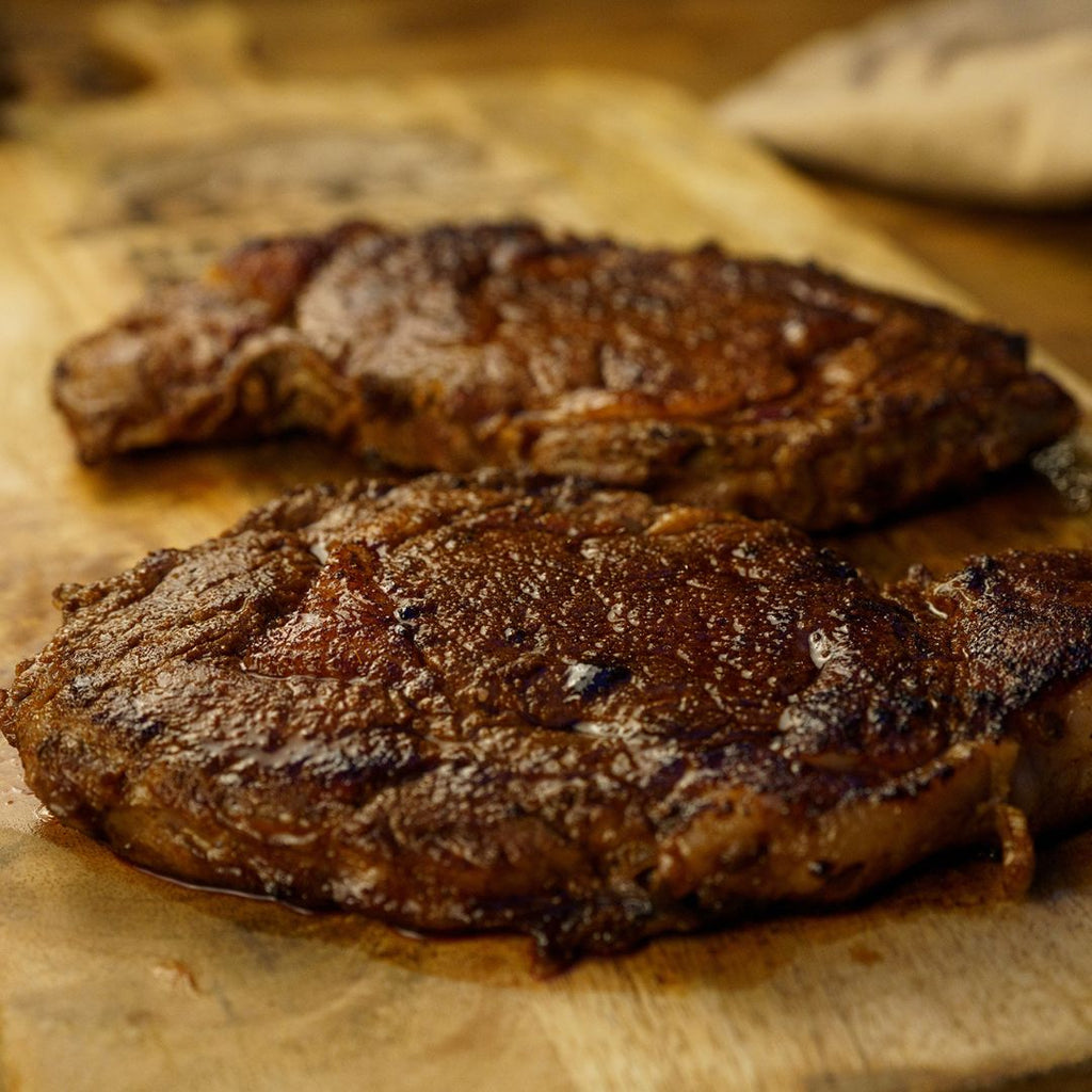 Side view of 2 bison steaks resting on a cutting board.